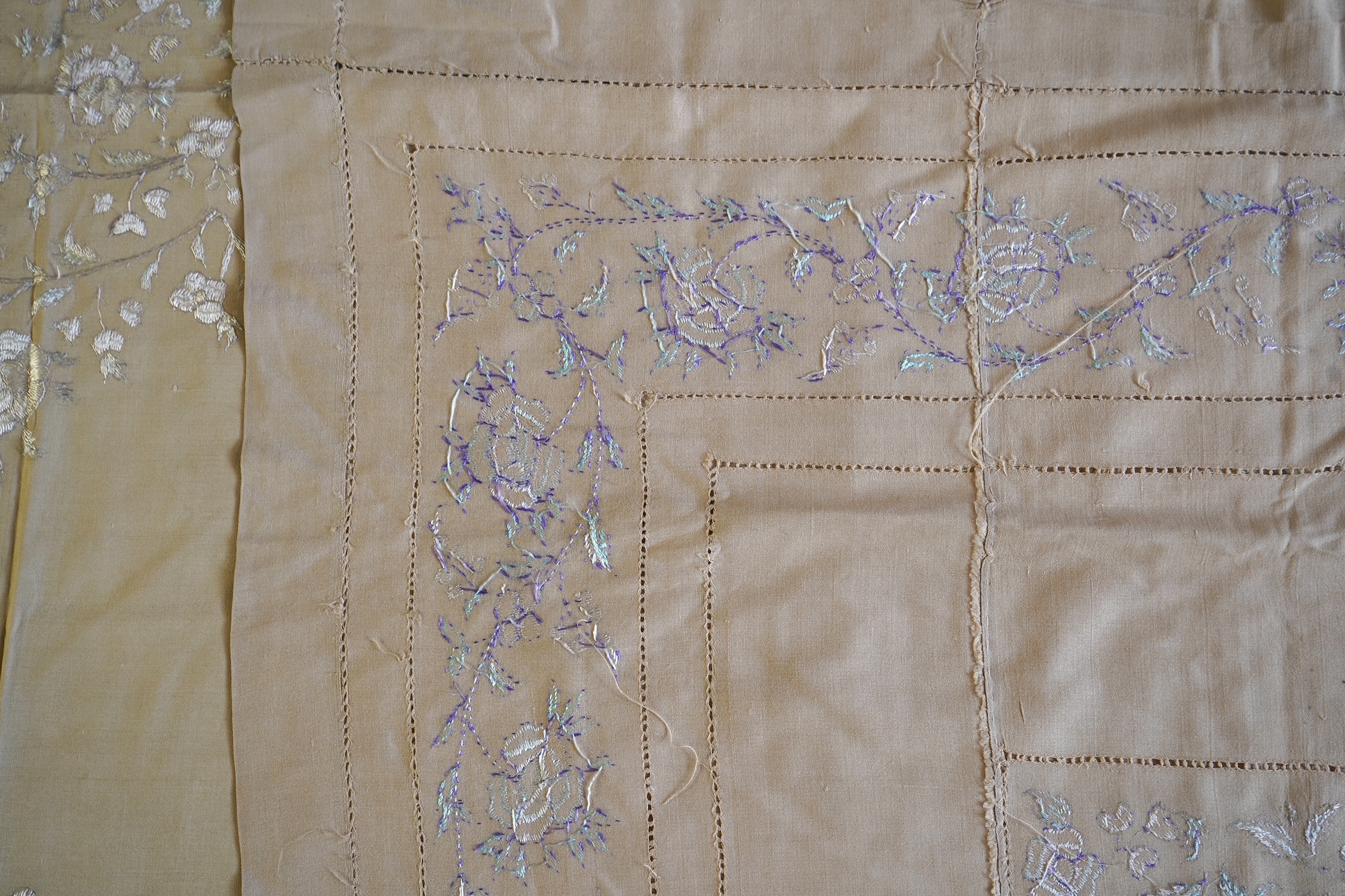A 1920’s heavy shantung silk hand embroidered table cover. Worked with decorative rows of button hole stitch. Embroidered with white, green and blue silk flowers. 240cm x 204cm. Condition - some fine holes near corners,